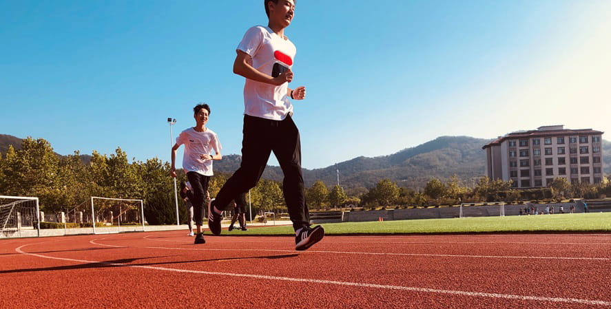 Teenagers running on track on school campus
