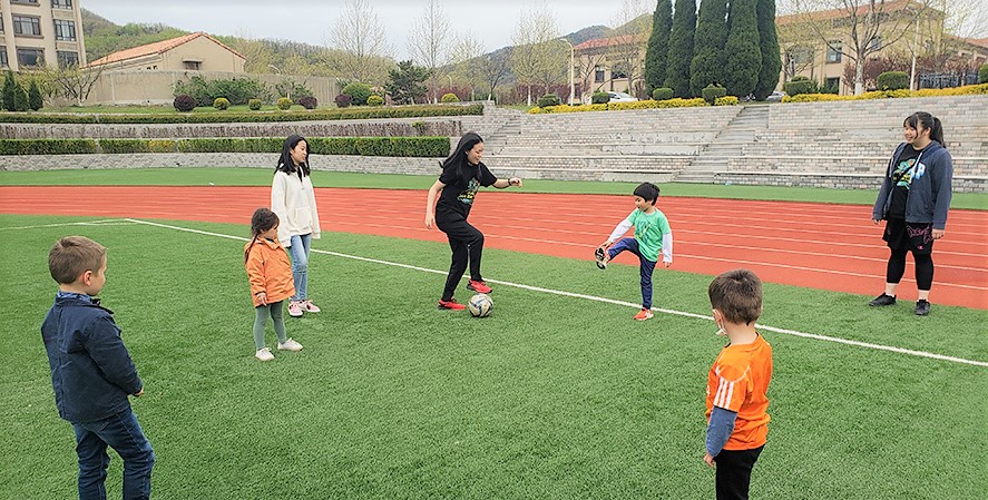 Girls playing soccer with small children